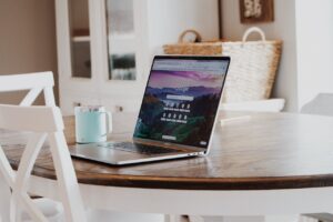 A sleek laptop on a wooden table with a mug, exemplifying a modern home workspace.